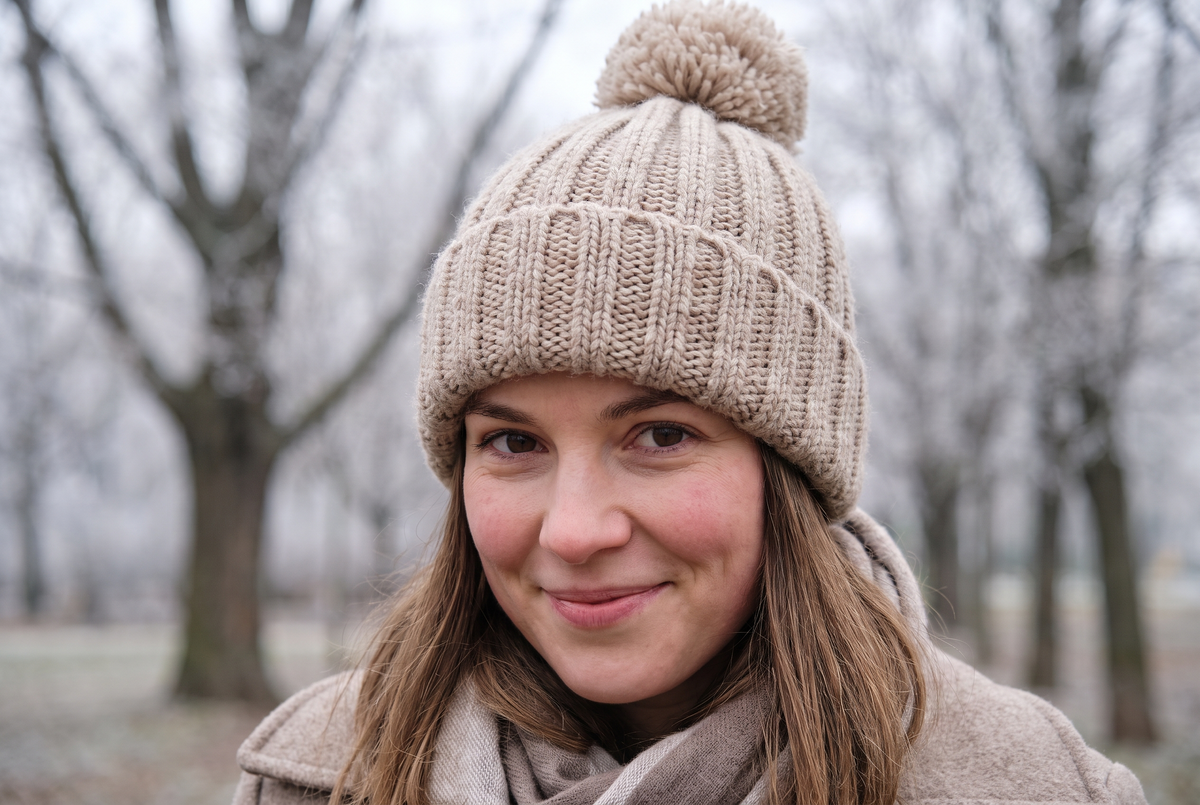 Femme souriante portant un bonnet côtelé beige à pompon dans un parc en hiver Image